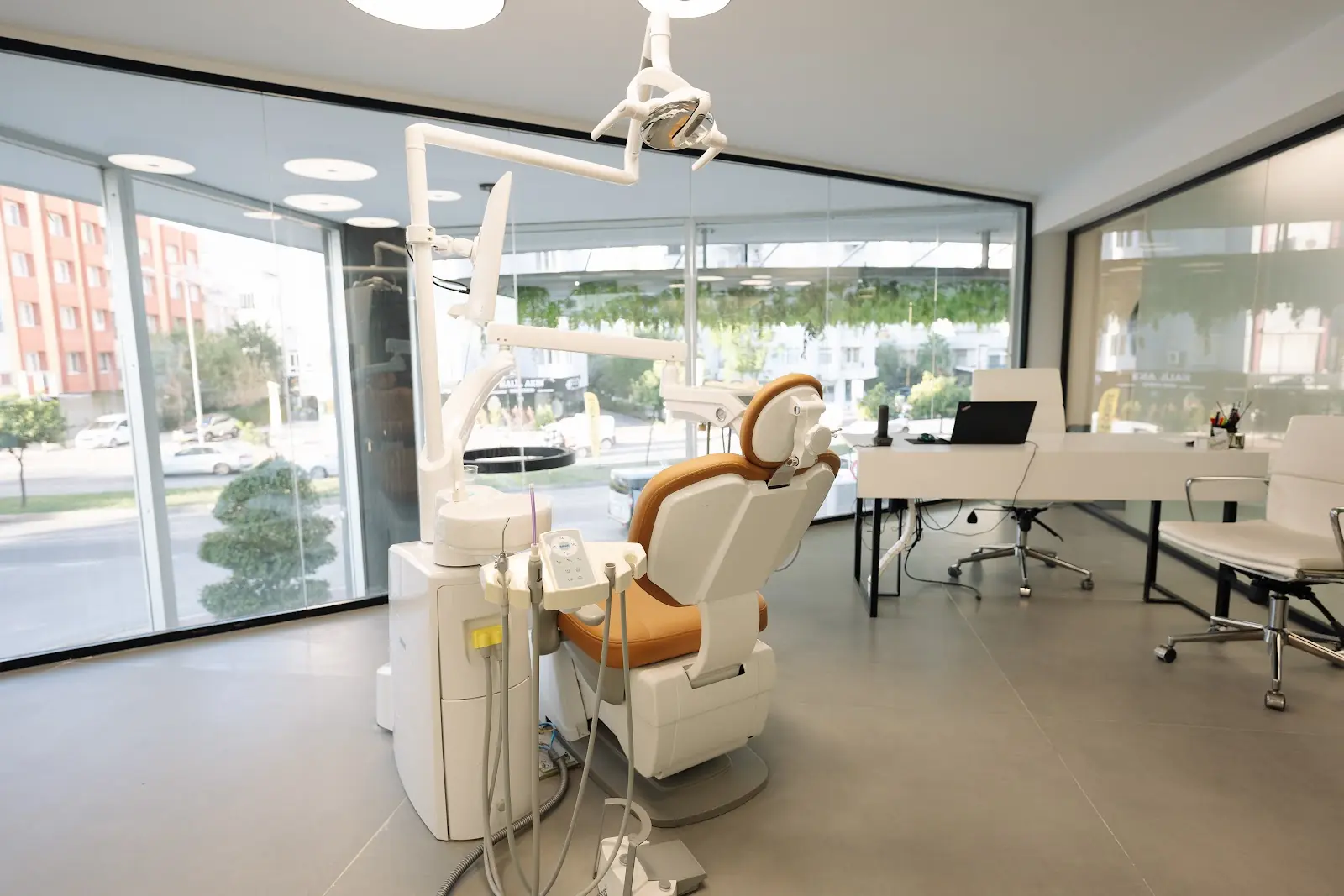 A dental chair and overhead light beside a window.