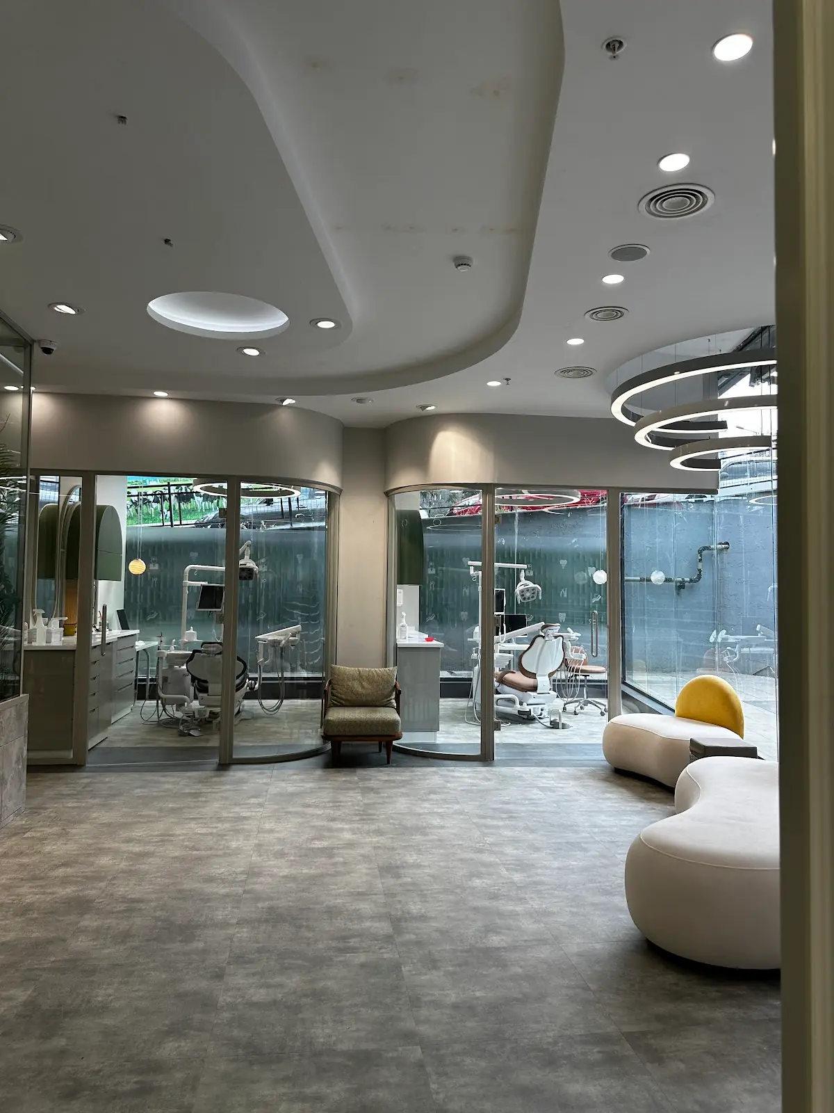 Glass-partitioned rooms and seating in a dental clinic.
